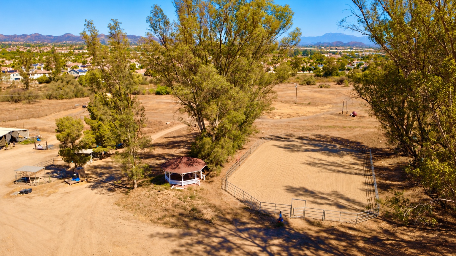 Aerial view of the riding arena beside a gazebo and trees at Silver Star Ranch