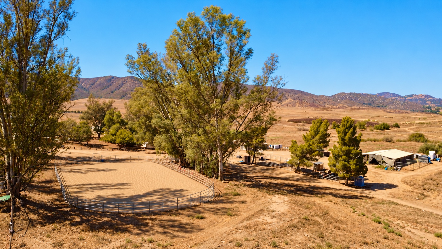 Riding arena, shade trees and open hills at Silver Star Ranch
