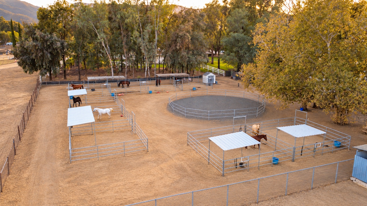 Aerial view of horses in spacious sheltered stalls around a round pen at Silver Star Ranch